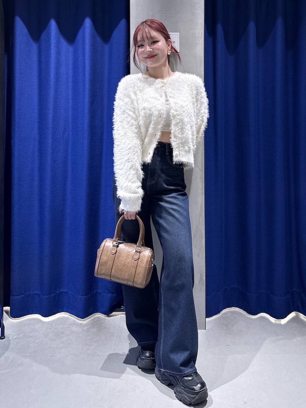 ブラック系のスニーカー、ブルー系のスラックス、ブラウン系のボストンバッグを着用したレディースの冬コーディネートの2枚目の写真