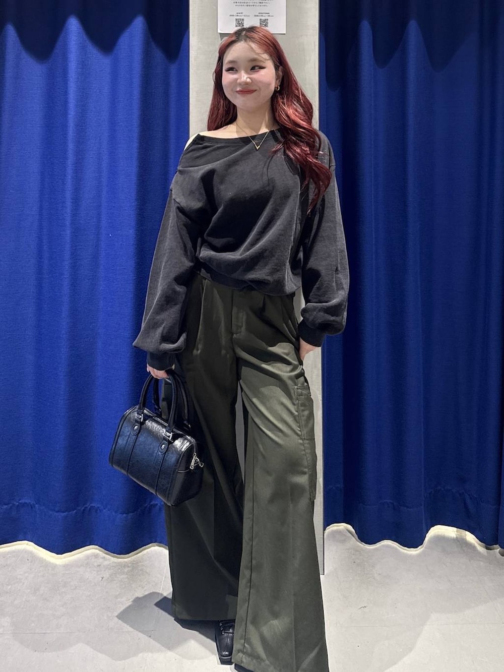 ブラック系のボストンバッグ、グリーン系のスラックス、ブラック系のサンダルを着用したレディースの冬コーディネートの2枚目の写真