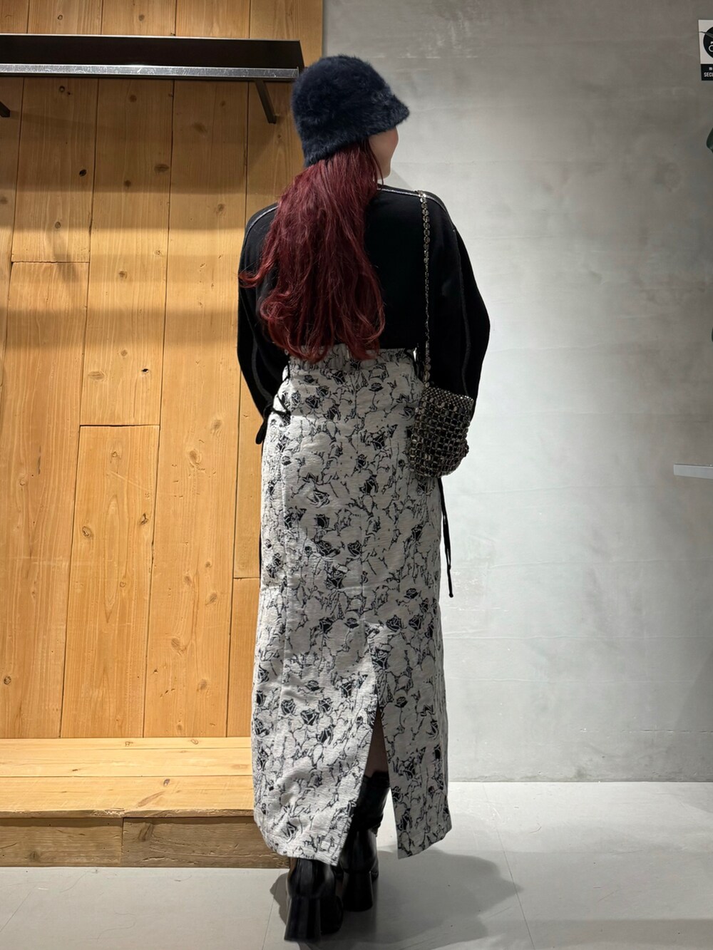 ブラック系のニット/セーター、ホワイト系のスカート、ブラック系のブーツを着用したレディースの秋コーディネートの5枚目の写真