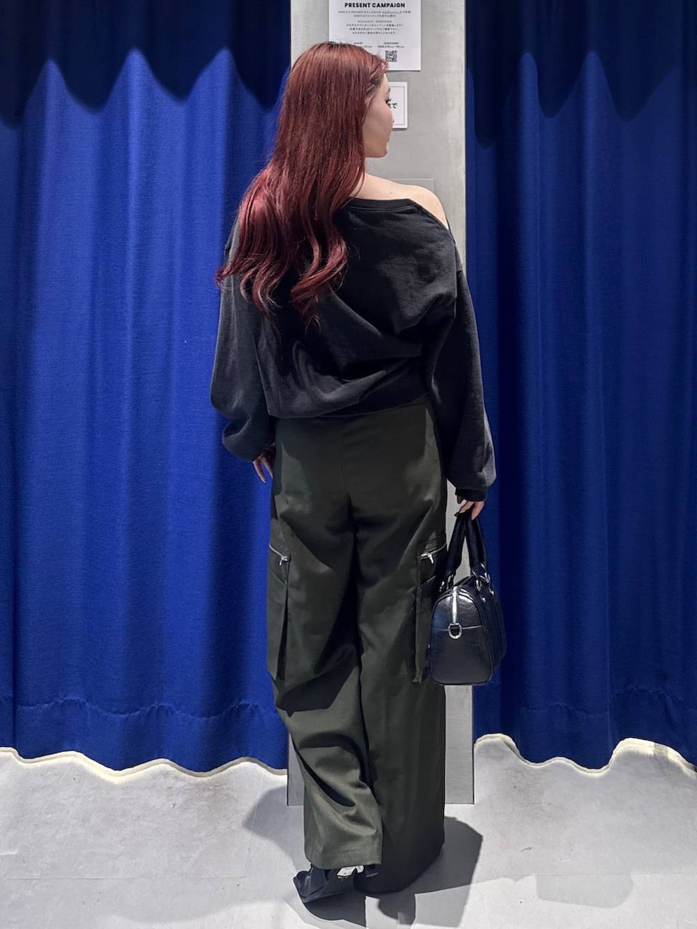 ブラック系のボストンバッグ、グリーン系のスラックス、ブラック系のサンダルを着用したレディースの冬コーディネートの3枚目の写真