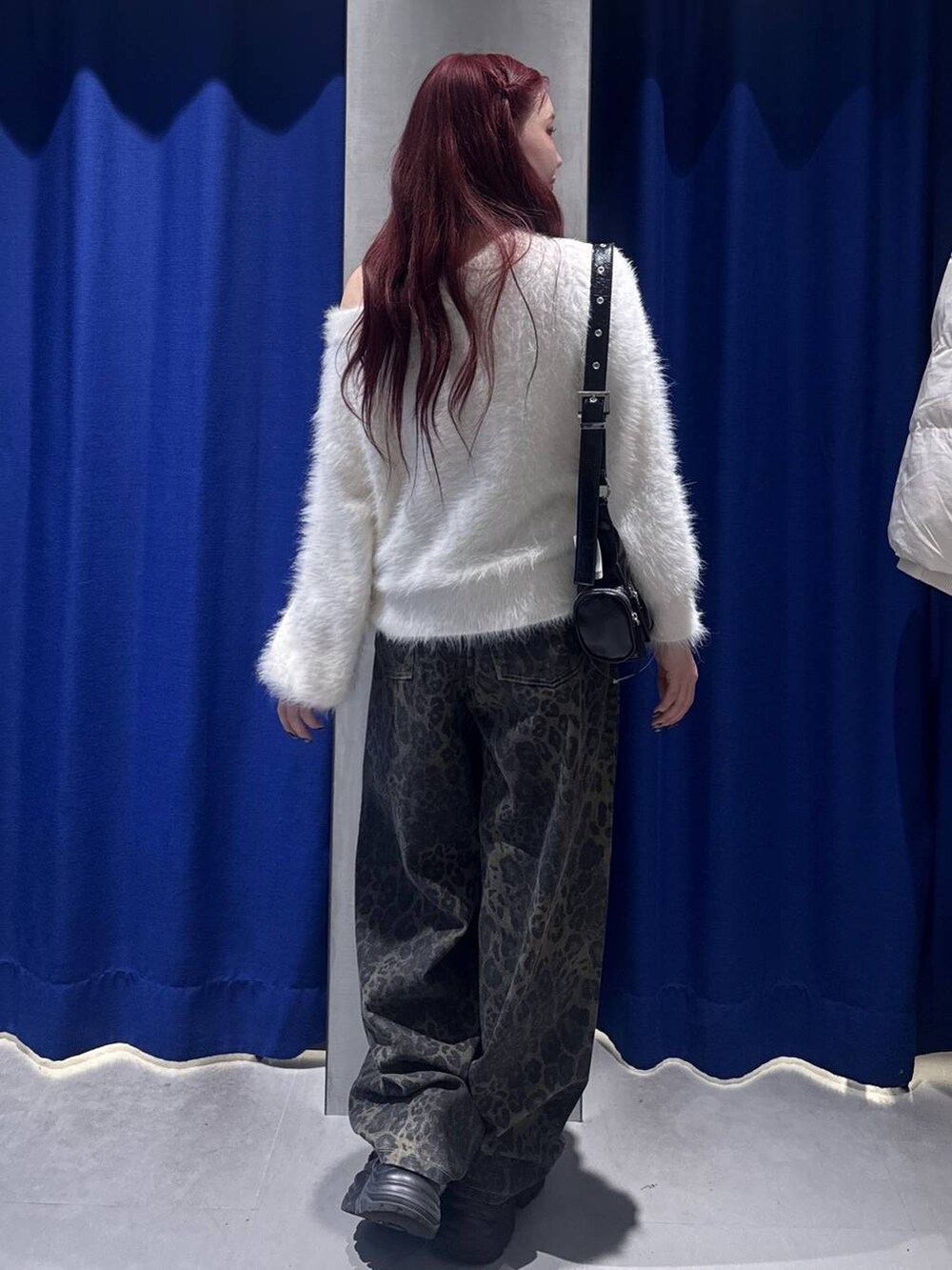 ブラック系のスニーカー、ホワイト系のニット/セーター、ブラック系のショルダーバッグを着用したレディースの冬コーディネートの3枚目の写真