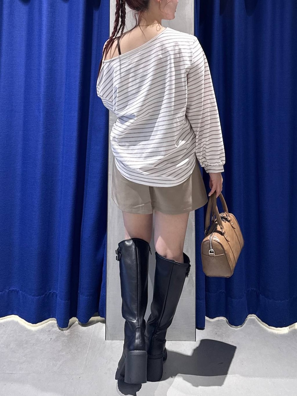 ブラック系のブーツ、ブラウン系のスカート、ブラウン系のボストンバッグを着用したレディースの冬コーディネートの3枚目の写真