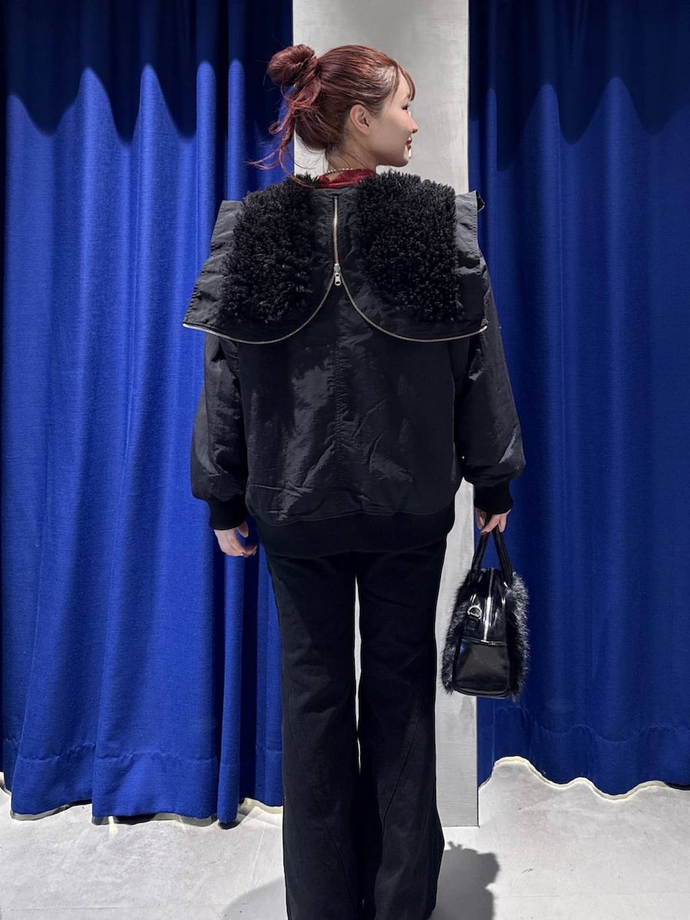 ブラック系のデニムパンツ、ブラック系のブルゾン、レッド系のニット/セーターを着用したレディースの秋コーディネートの5枚目の写真