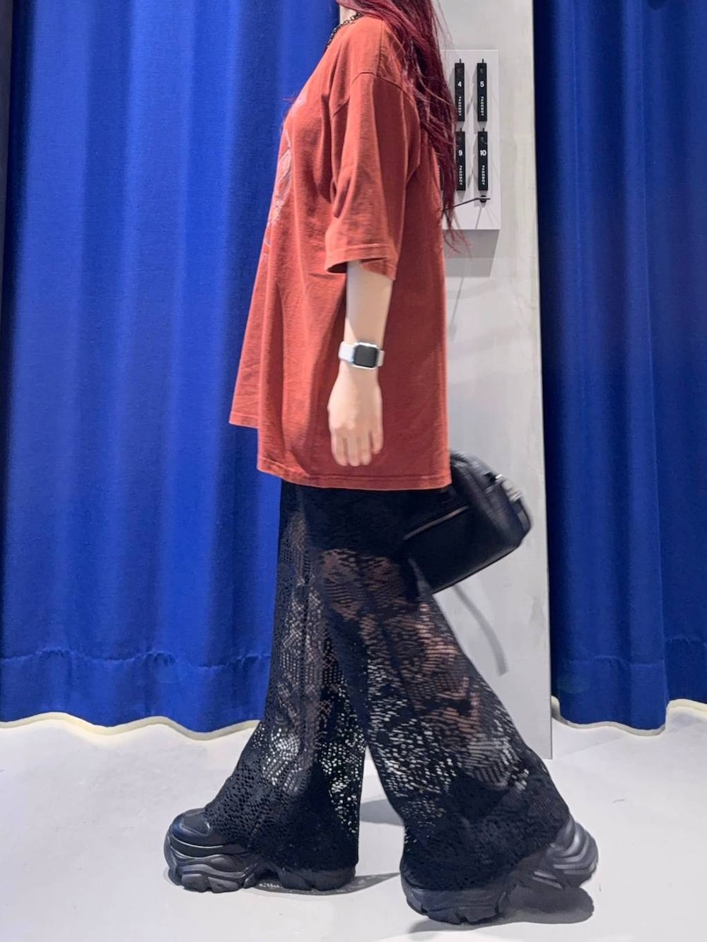 ブラック系のスニーカー、レッド系のTシャツ/カットソー、ブラック系のショルダーバッグを着用したレディースの夏コーディネートの3枚目の写真