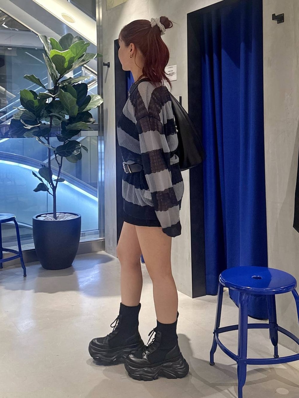 ブラック系のブーツ、ブラック系のトートバッグ、ブラック系のスラックスを着用したレディースの春コーディネートの3枚目の写真