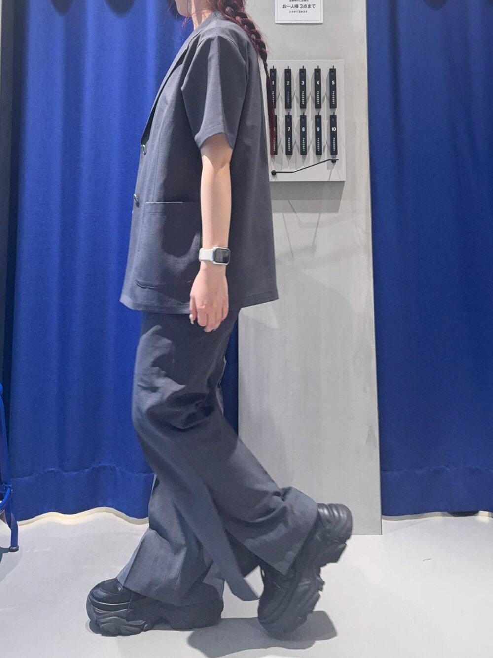 ブラック系のスニーカー、グリーン系のショルダーバッグ、ホワイト系のベストを着用したレディースの夏コーディネートの3枚目の写真