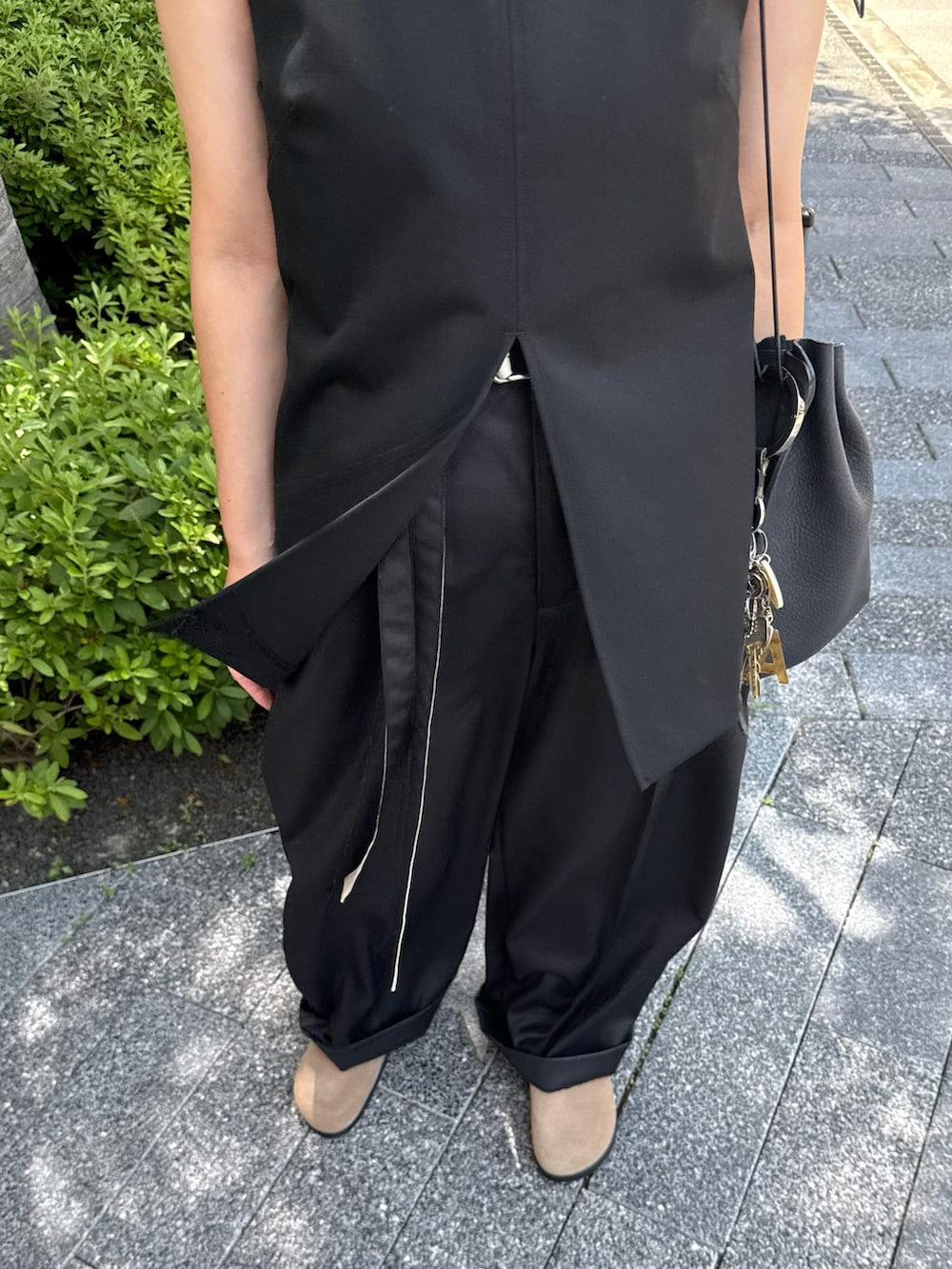 ブラック系のスラックスを着用したレディースの夏コーディネートの2枚目の写真