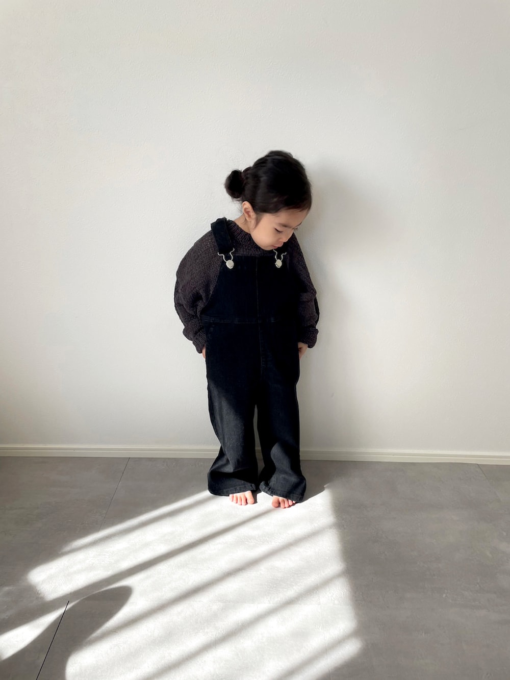グレー系のニット/セーター、ブラック系のサロペット/オーバーオールを着用したキッズの春コーディネートの2枚目の写真