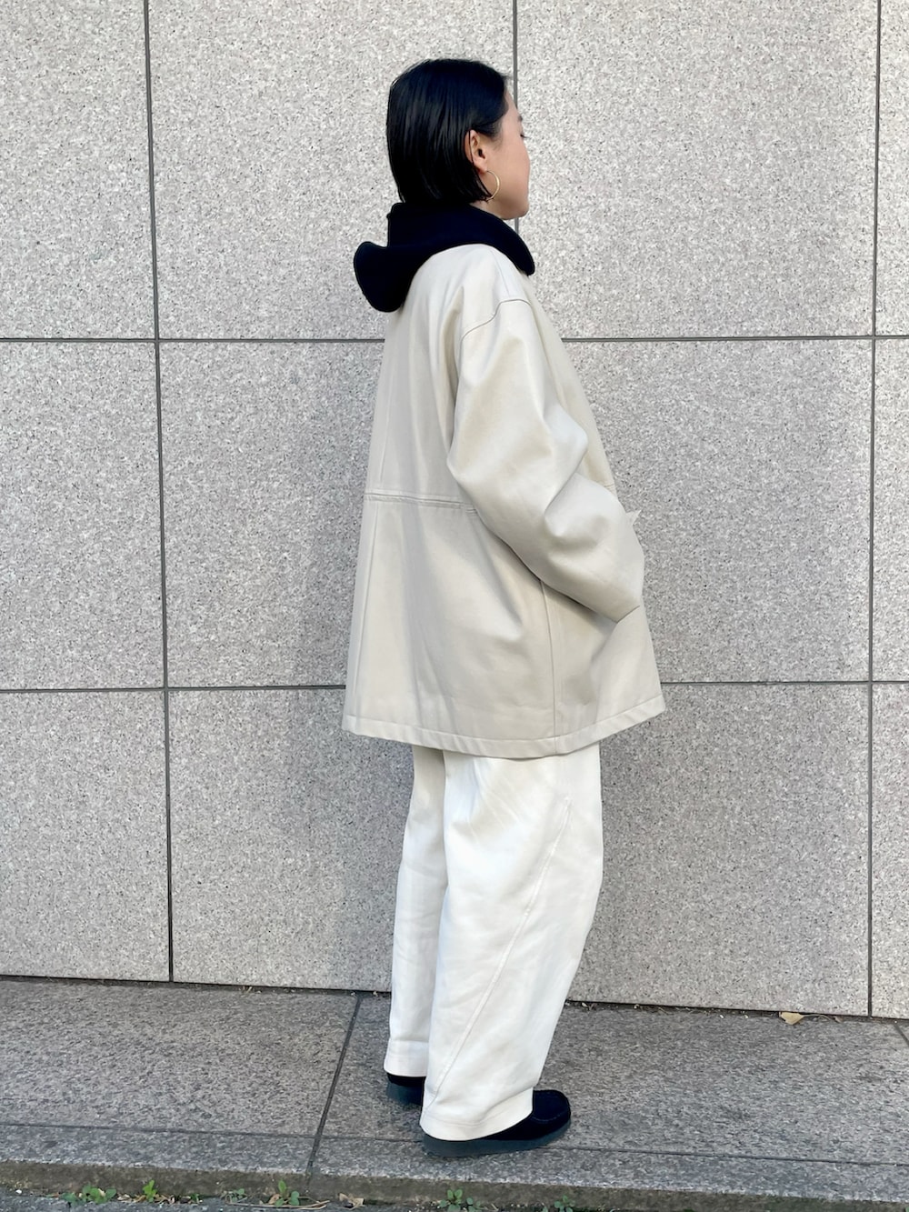 ベージュ系のカバーオール、ブラック系のパーカーを着用したレディースの冬コーディネートの2枚目の写真