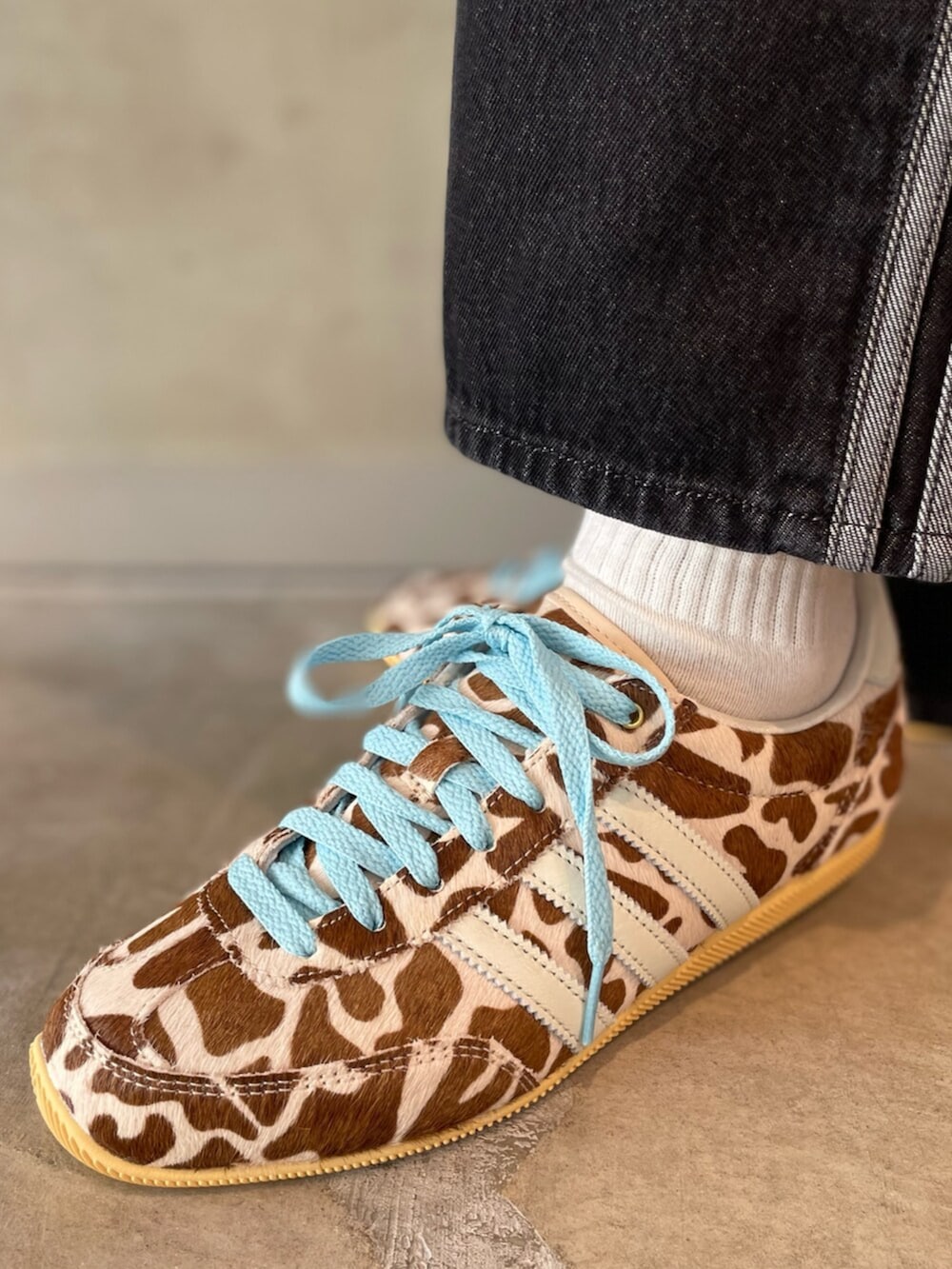 ブラック系のデニムパンツ、ブルー系のナイロンジャケット、ベージュ系のスニーカーを着用したレディースの春コーディネートの6枚目の写真