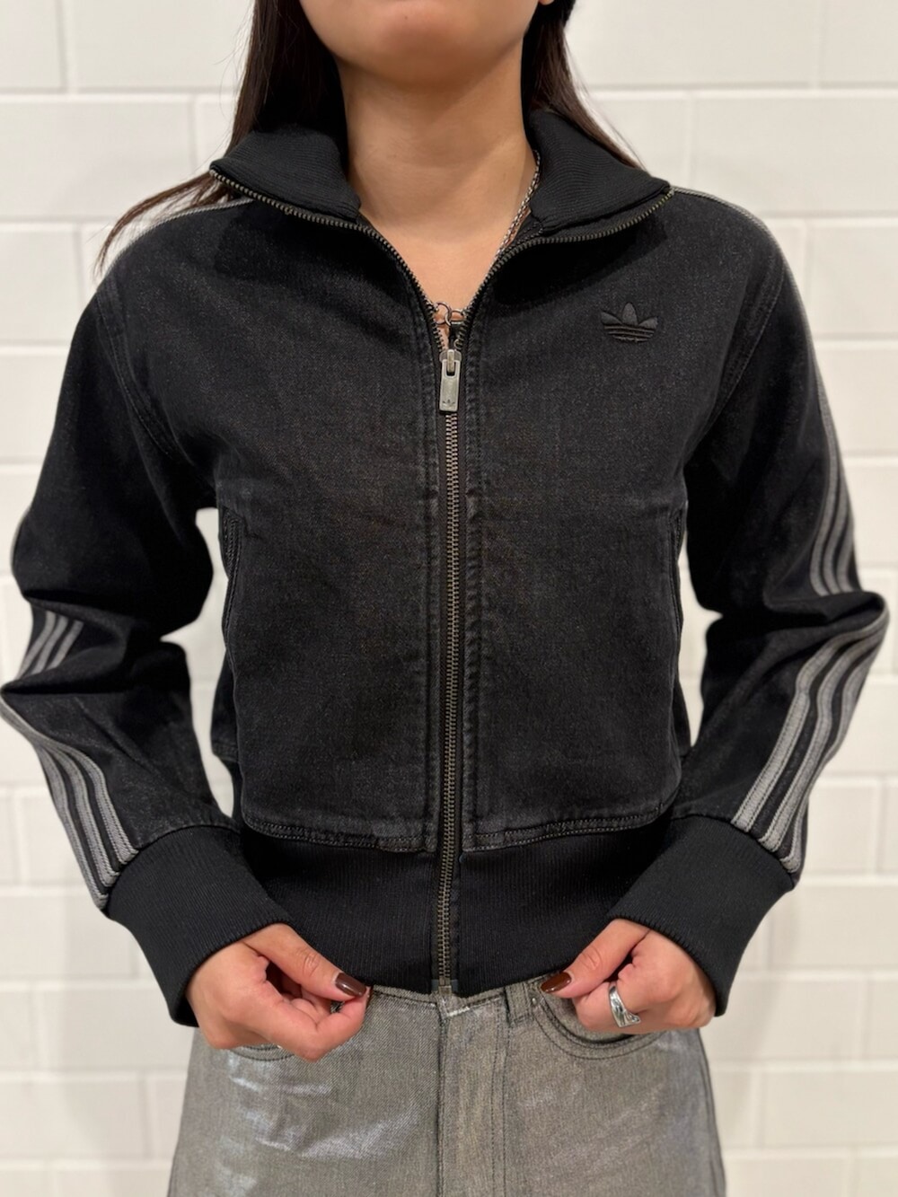 ブラック系のデニムジャケット、ブラック系のスニーカー、シルバー系のデニムパンツを着用したレディースの冬コーディネートの4枚目の写真