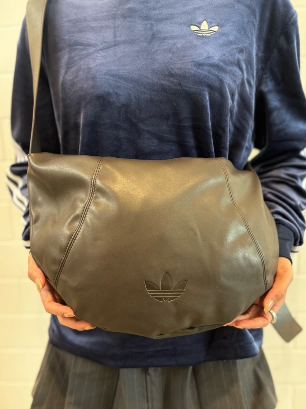 ブラウン系のショルダーバッグ、ベージュ系のスニーカー、ブルー系のポロシャツを着用したレディースの春コーディネートの5枚目の写真