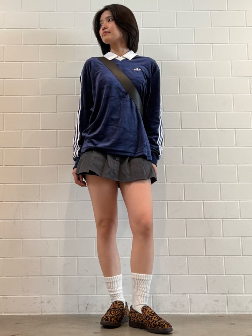 ブラウン系のショルダーバッグ、ベージュ系のスニーカー、ブルー系のポロシャツを着用したレディースの春コーディネートの3枚目の写真