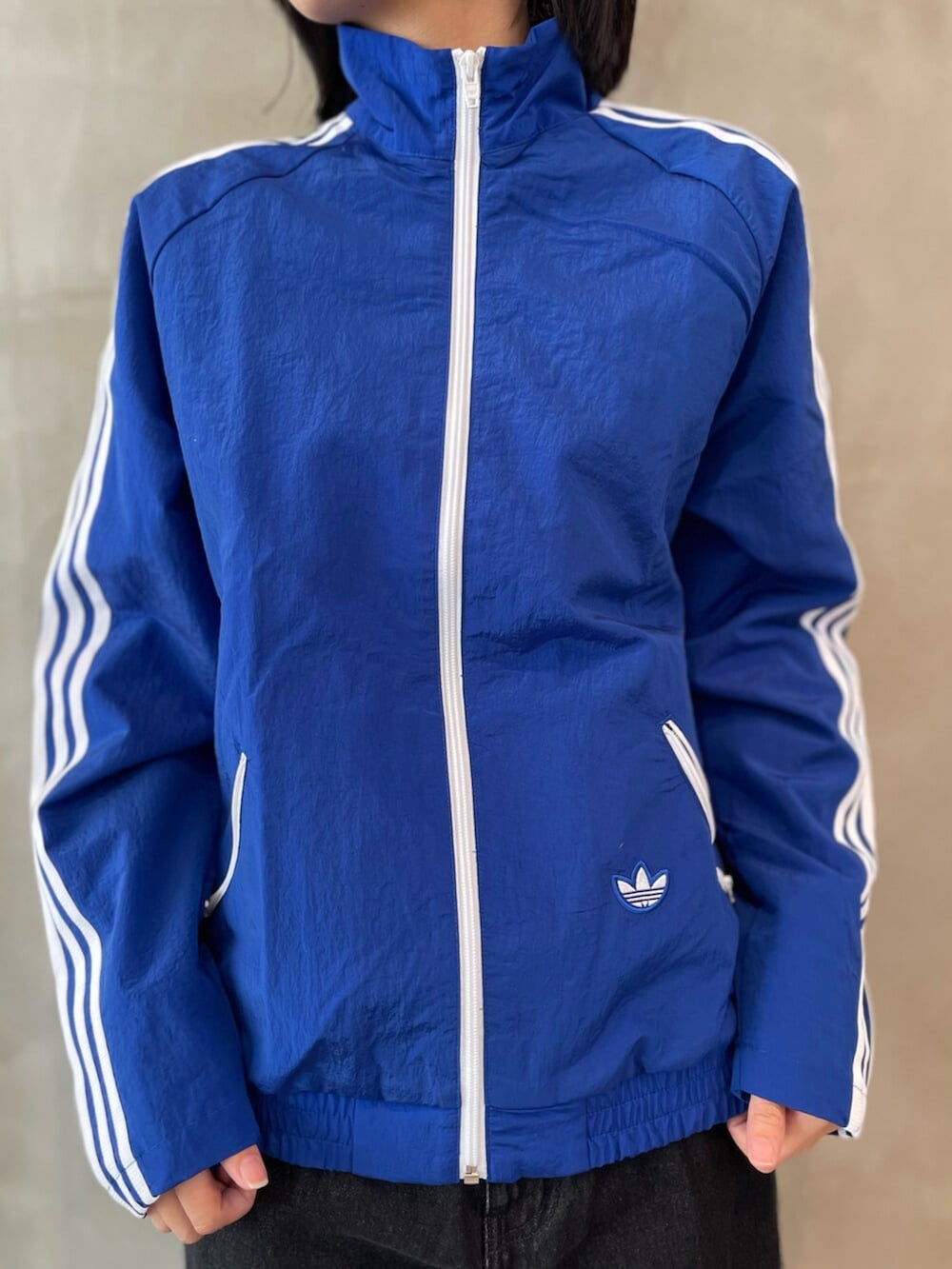 ブラック系のデニムパンツ、ブルー系のナイロンジャケット、ベージュ系のスニーカーを着用したレディースの春コーディネートの4枚目の写真