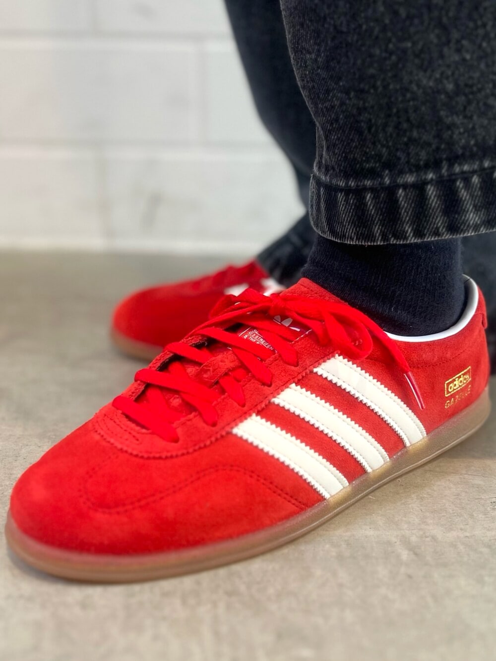 ブラック系のデニムパンツ、イエロー系のスウェット、レッド系のスニーカーを着用したレディースの秋コーディネートの6枚目の写真