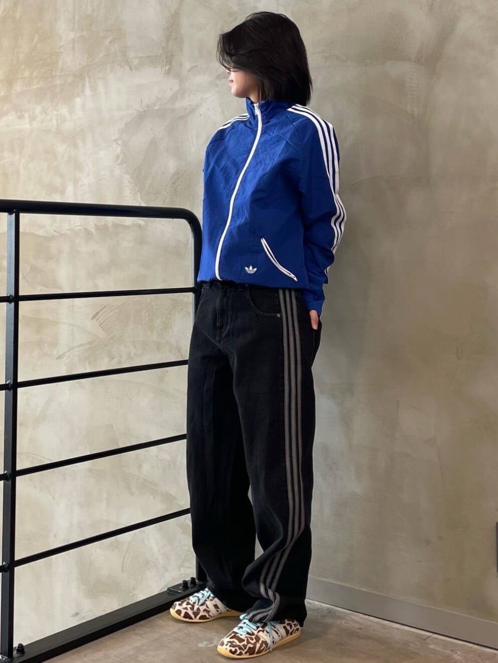 ブラック系のデニムパンツ、ブルー系のナイロンジャケット、ベージュ系のスニーカーを着用したレディースの春コーディネートの3枚目の写真