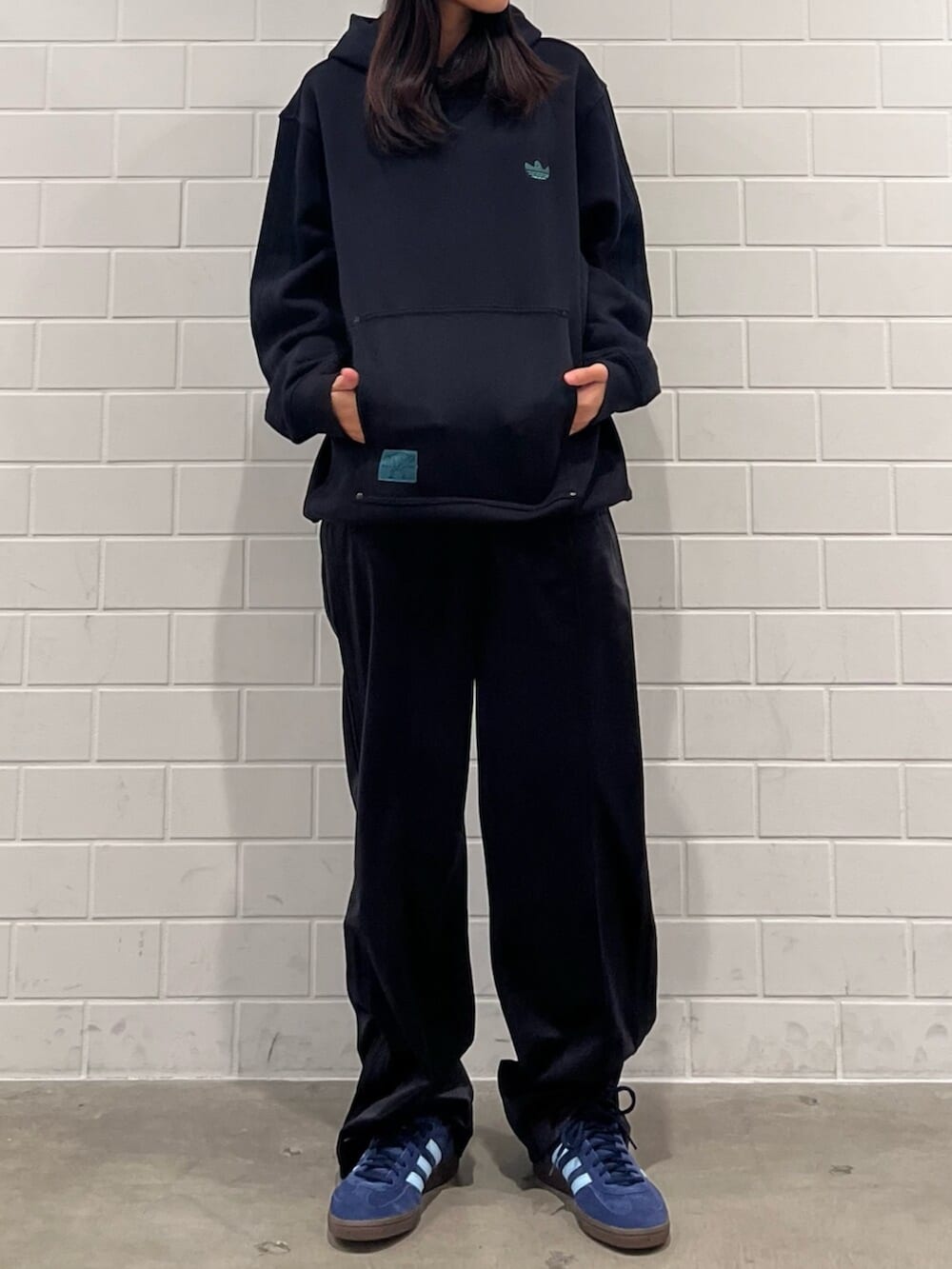 ブラック系のスウェットパンツ、ブルー系のスニーカー、ブラック系のトップスを着用したレディースの秋コーディネートの2枚目の写真