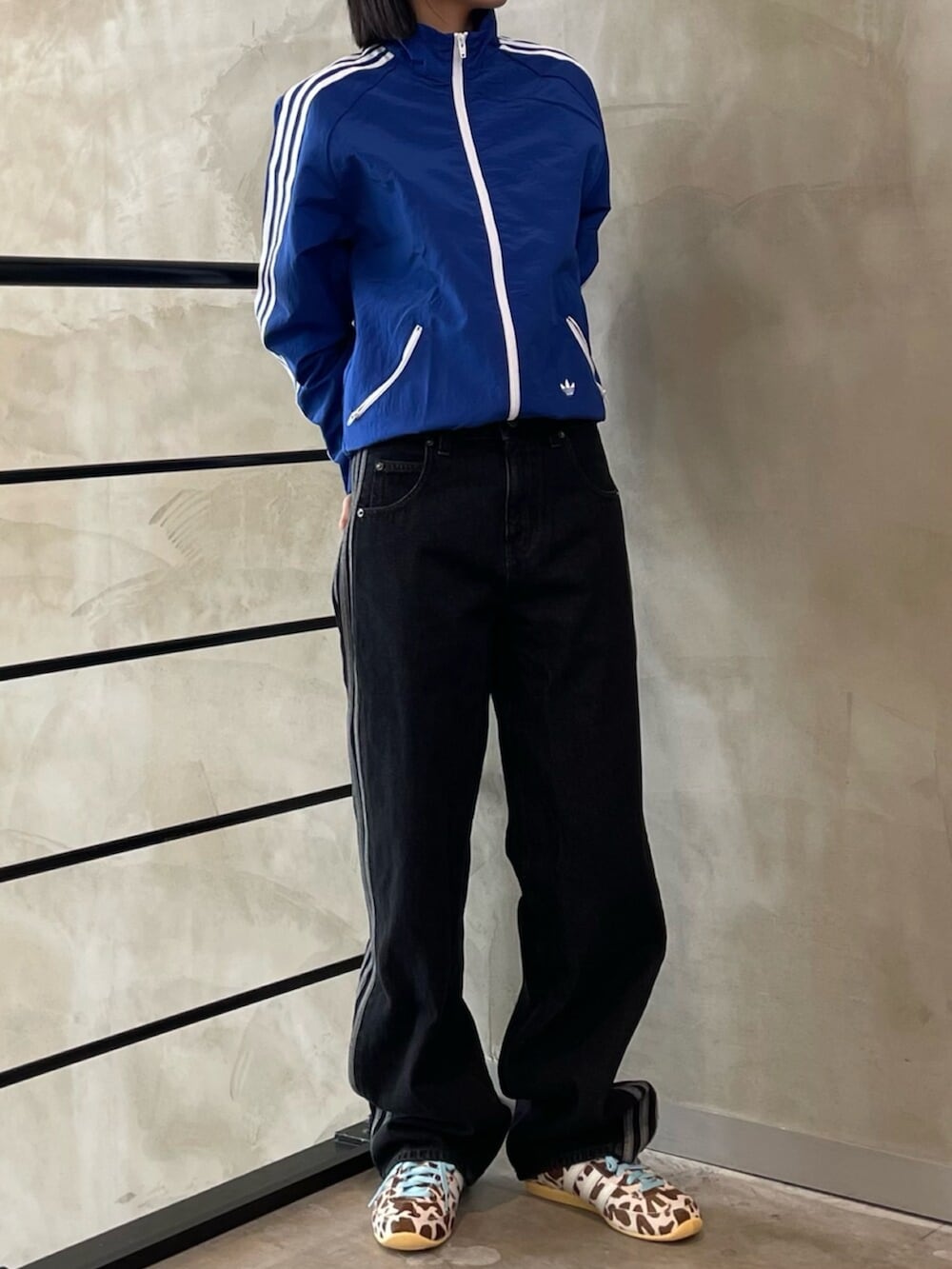 ブラック系のデニムパンツ、ブルー系のナイロンジャケット、ベージュ系のスニーカーを着用したレディースの春コーディネートの2枚目の写真