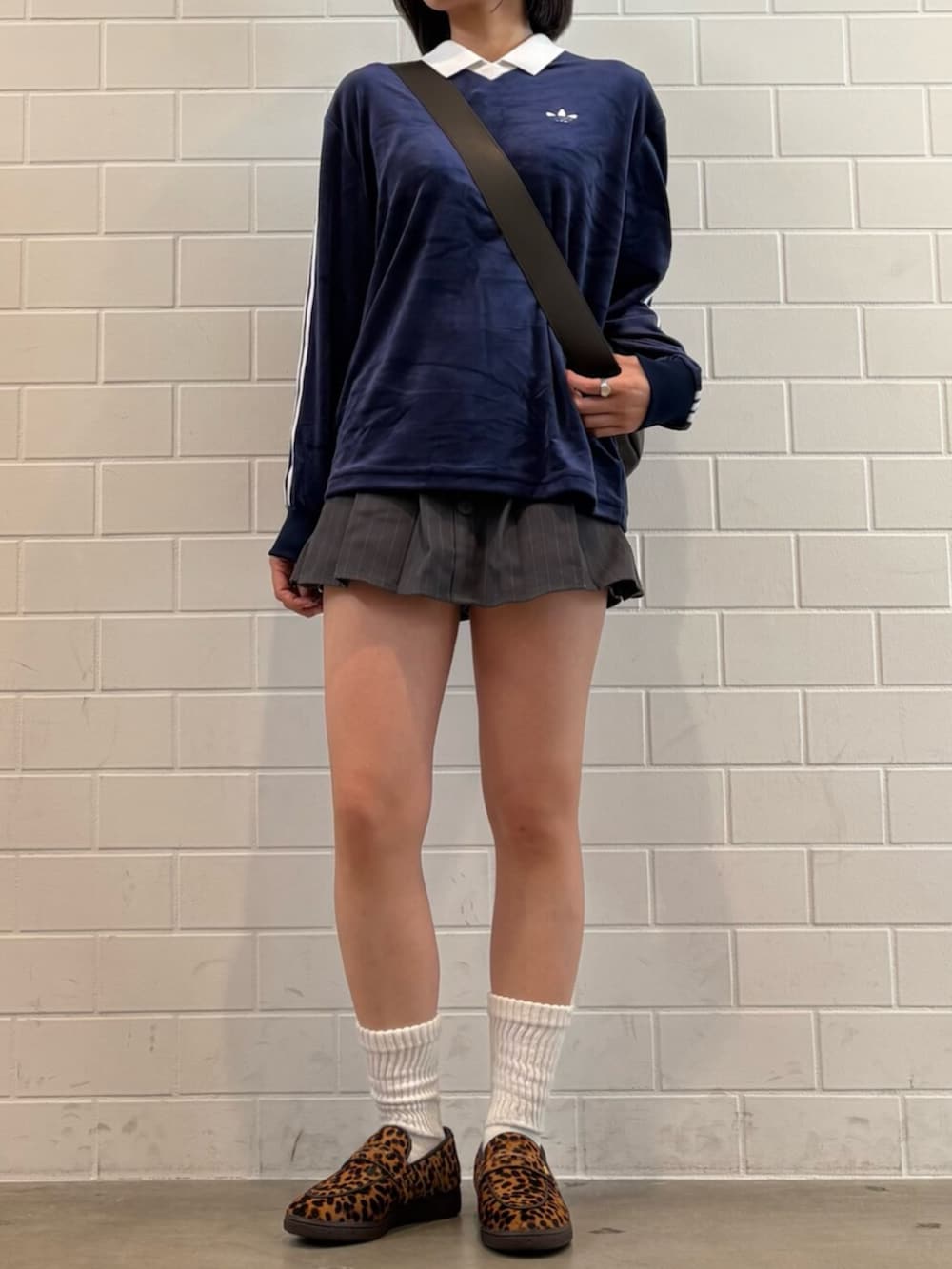 ブラウン系のショルダーバッグ、ベージュ系のスニーカー、ブルー系のポロシャツを着用したレディースの春コーディネートの2枚目の写真