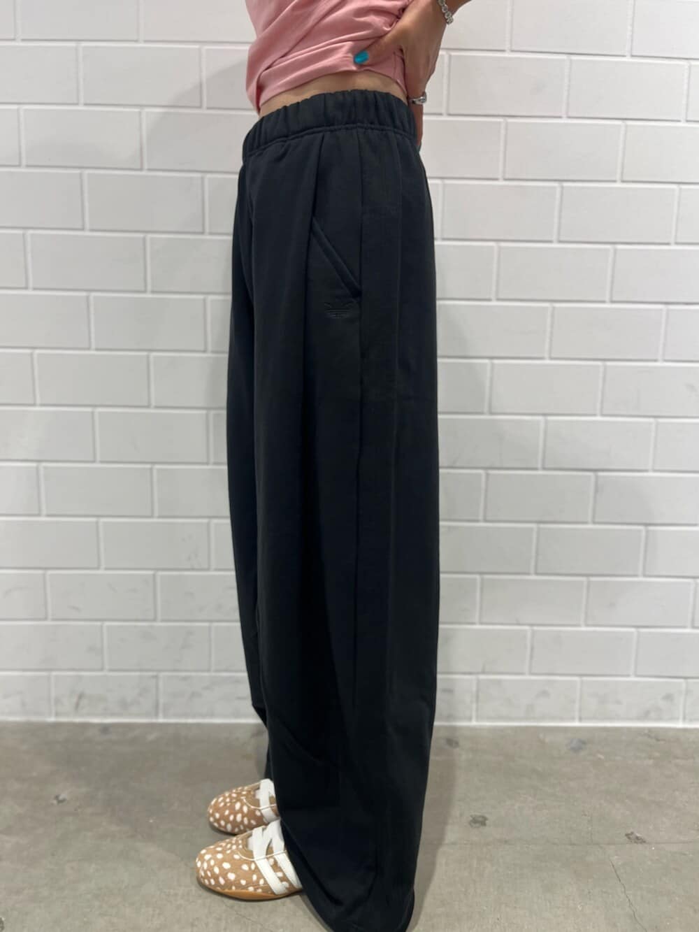 ブラック系のその他パンツ、ブラウン系のスニーカー、ベージュ系のハンドバッグを着用したレディースの秋コーディネートの5枚目の写真