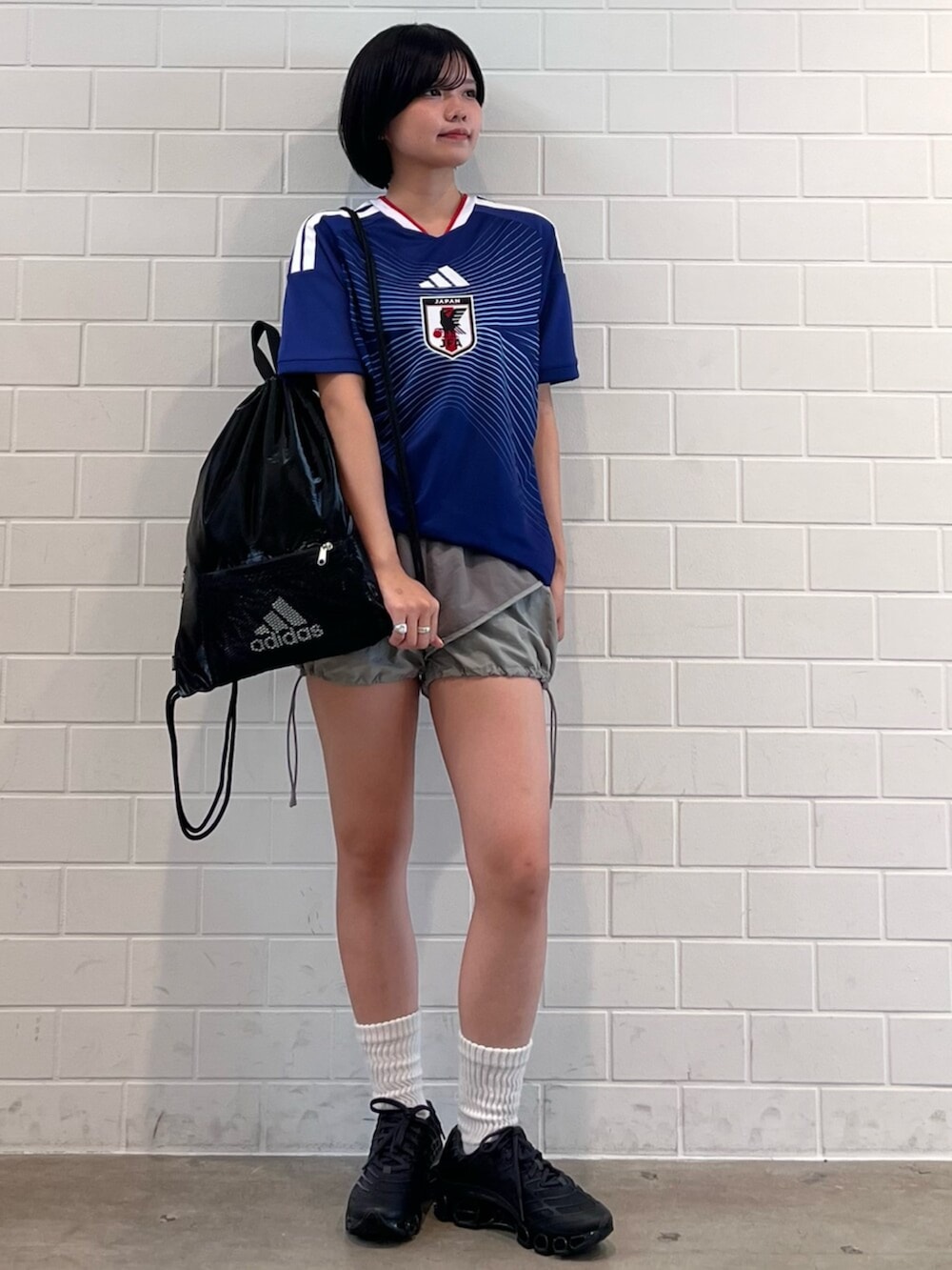 グレー系のスニーカー、ブラック系のエコバッグ/サブバッグ、ブルー系のTシャツ/カットソーを着用したレディースの夏コーディネートの3枚目の写真
