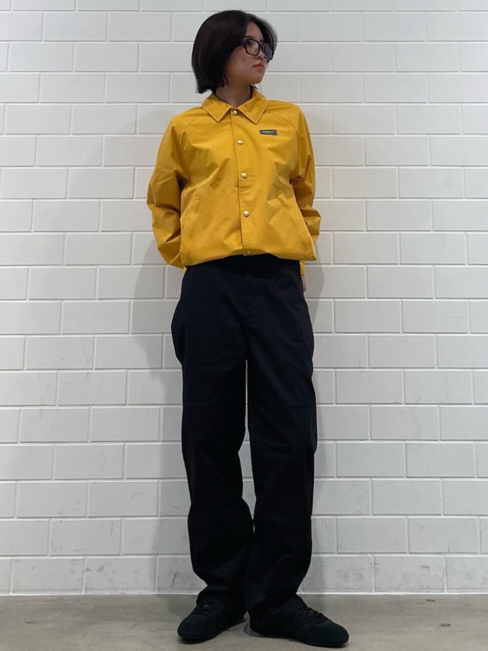 イエロー系のブルゾン、ブラック系のその他パンツ、ブラック系のスニーカーを着用したレディースの冬コーディネートの3枚目の写真