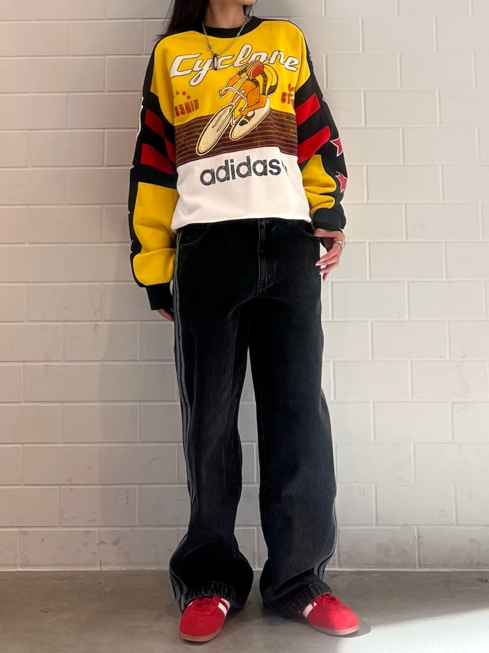 ブラック系のデニムパンツ、イエロー系のスウェット、レッド系のスニーカーを着用したレディースの秋コーディネートの2枚目の写真