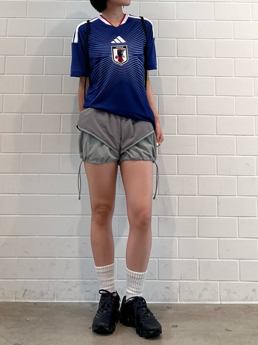 グレー系のスニーカー、ブラック系のエコバッグ/サブバッグ、ブルー系のTシャツ/カットソーを着用したレディースの夏コーディネートの2枚目の写真