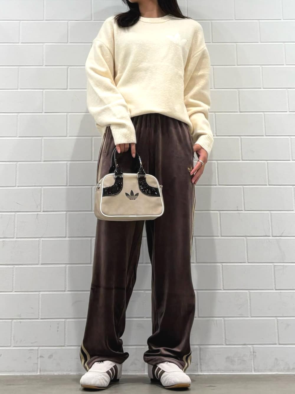 ブラウン系のパンツ、ホワイト系のニット/セーター、ベージュ系のショルダーバッグを着用したレディースの秋コーディネートの2枚目の写真