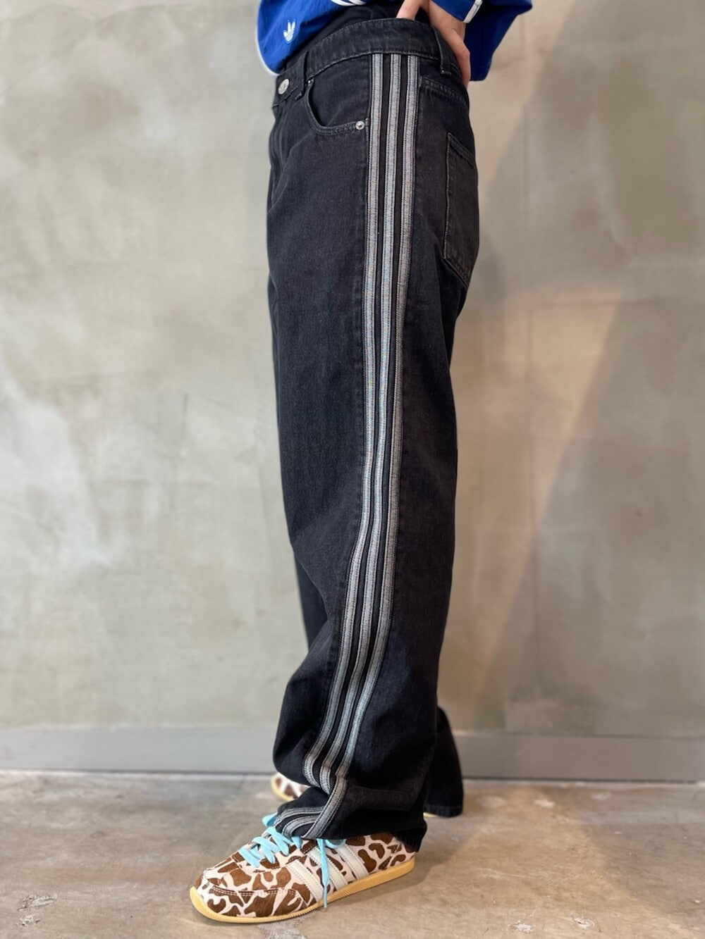 ブラック系のデニムパンツ、ブルー系のナイロンジャケット、ベージュ系のスニーカーを着用したレディースの春コーディネートの5枚目の写真