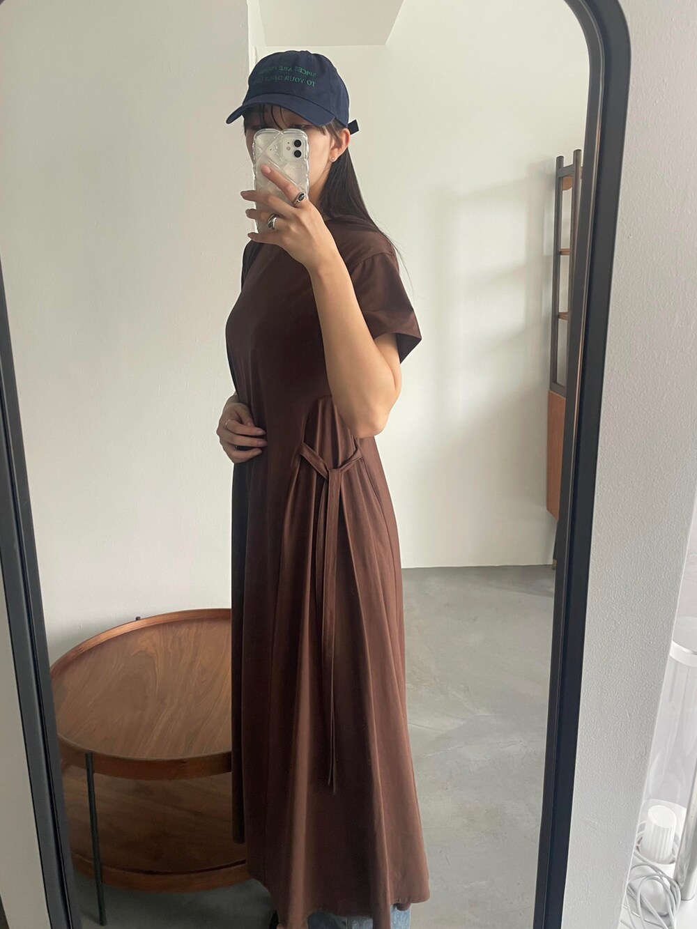 グレー系のデニムパンツ、ブラウン系のワンピース、ブルー系のキャップを着用したレディースの夏コーディネートの2枚目の写真