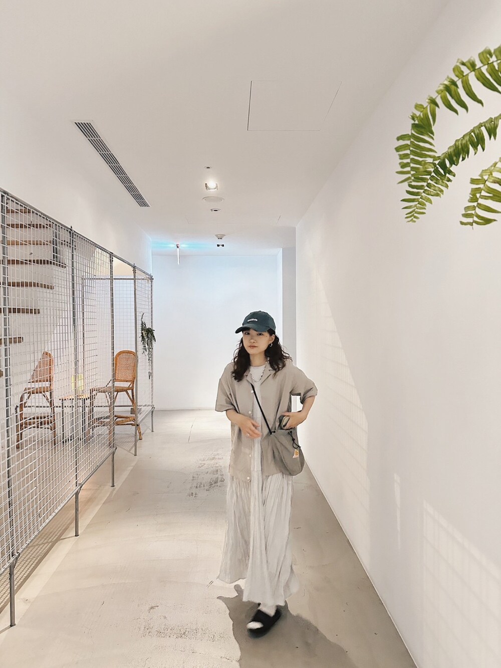 グレー系のドラムバッグ、ブルー系のシャツ/ブラウス、ブルー系のキャップを着用したレディースの夏コーディネートの2枚目の写真