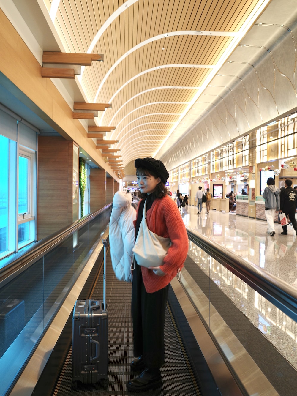 オレンジ系のカーディガン/ボレロ、ホワイト系のダウンジャケット/コート、ブラック系のブーツを着用したレディースの冬コーディネートの3枚目の写真