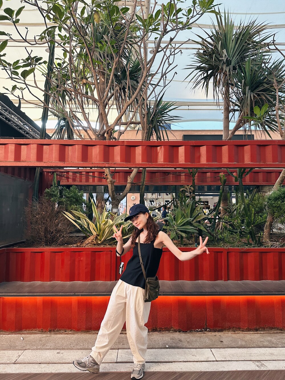 グリーン系のショルダーバッグ、グレー系のスニーカー、ブルー系のキャップを着用したレディースの夏コーディネートの3枚目の写真