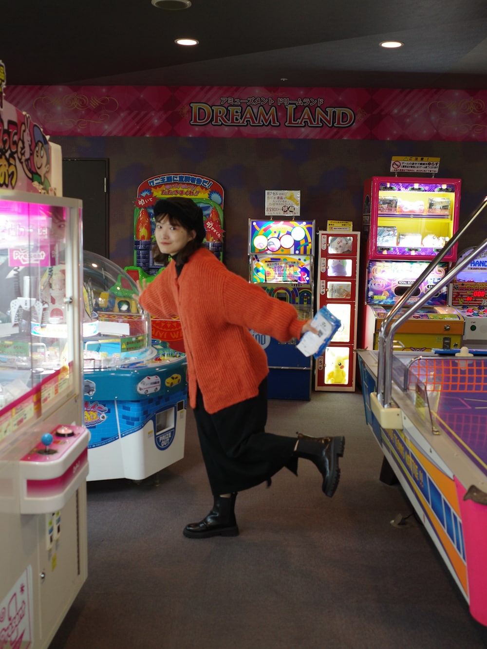 オレンジ系のカーディガン/ボレロ、ホワイト系のダウンジャケット/コート、ブラック系のブーツを着用したレディースの冬コーディネートの4枚目の写真