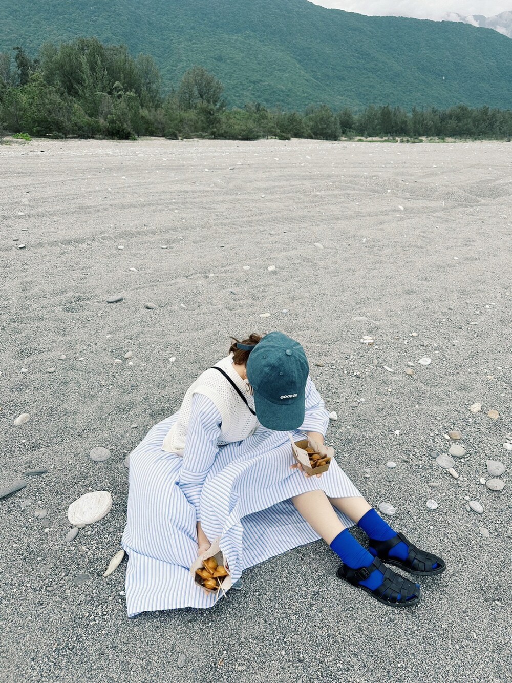 ブルー系のワンピース、グレー系のショルダーバッグ、ブルー系のキャップを着用したレディースの冬コーディネートの2枚目の写真