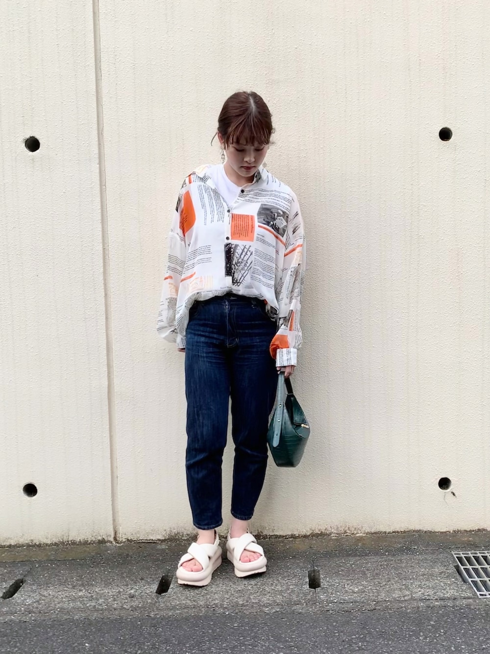 ブルー系のデニムパンツ、ホワイト系のサンダル、グリーン系のハンドバッグを着用したレディースの夏コーディネートの3枚目の写真