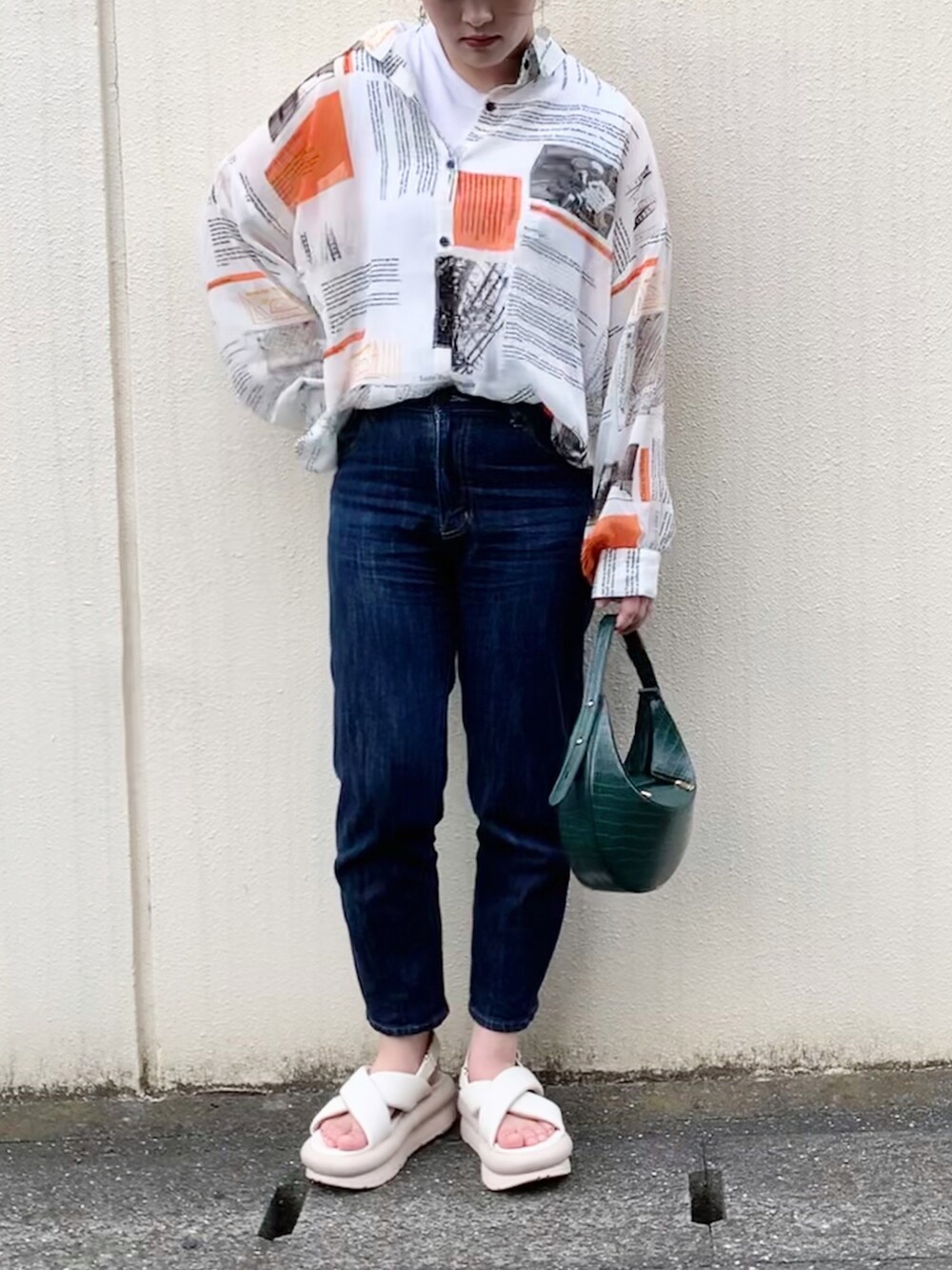 ブルー系のデニムパンツ、ホワイト系のサンダル、グリーン系のハンドバッグを着用したレディースの夏コーディネートの2枚目の写真