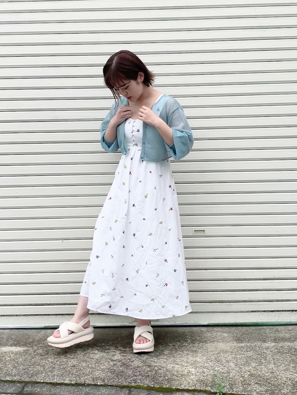 ホワイト系のワンピース、ブルー系のカーディガン/ボレロ、ホワイト系のサンダルを着用したレディースの夏コーディネートの3枚目の写真