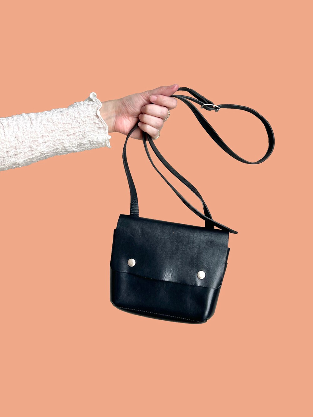 ブルー系のデニムパンツ、ブラック系のショルダーバッグ、ベージュ系のニット/セーターを着用したレディースの春コーディネートの2枚目の写真