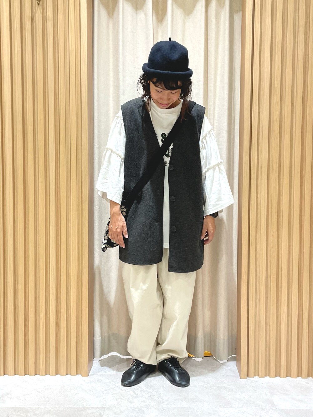 ブラウン系のベスト、ホワイト系のTシャツ/カットソー、ブラック系のハンドバッグを着用したレディースの秋コーディネートの3枚目の写真