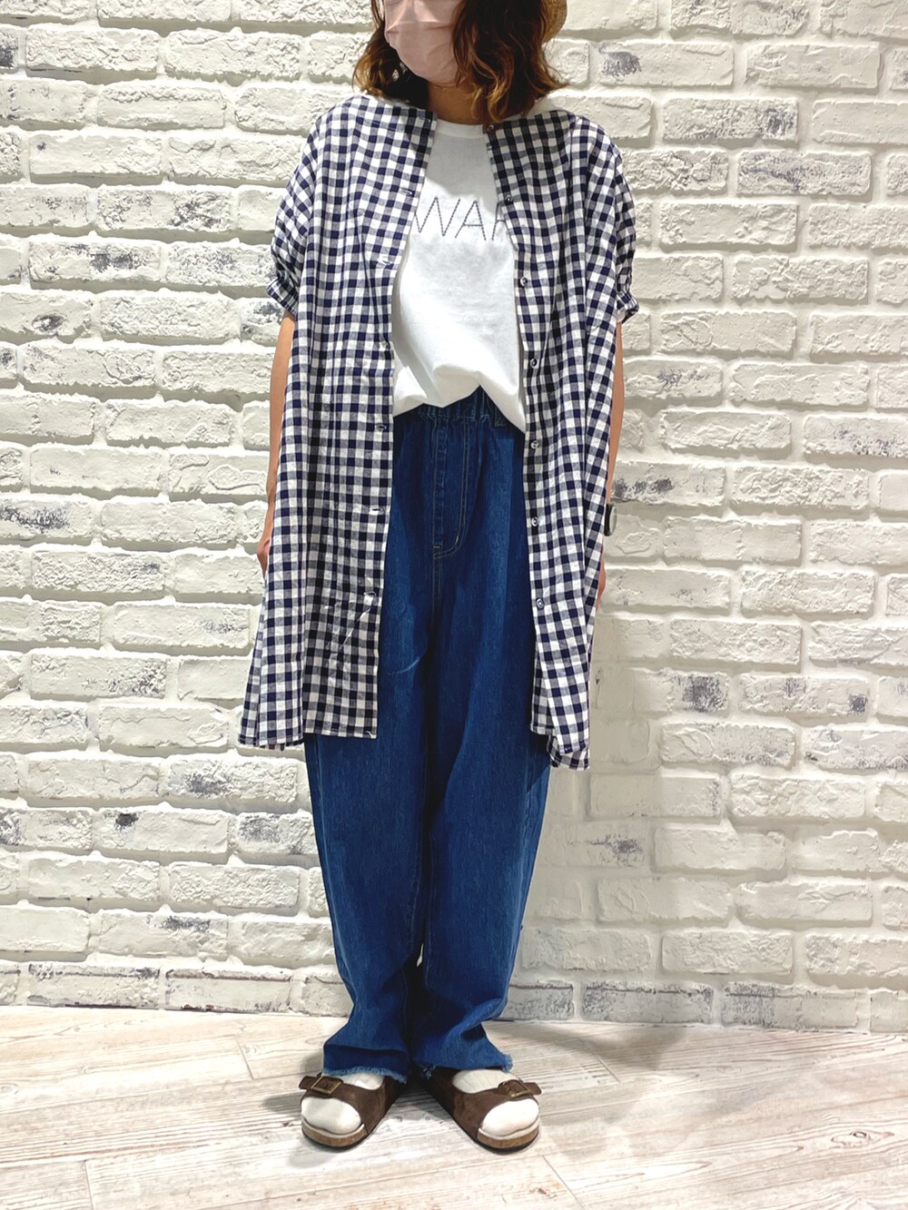 ホワイト系のTシャツ/カットソー、ブルー系のデニムパンツ、ブラウン系のサンダルを着用したレディースの夏コーディネートの2枚目の写真
