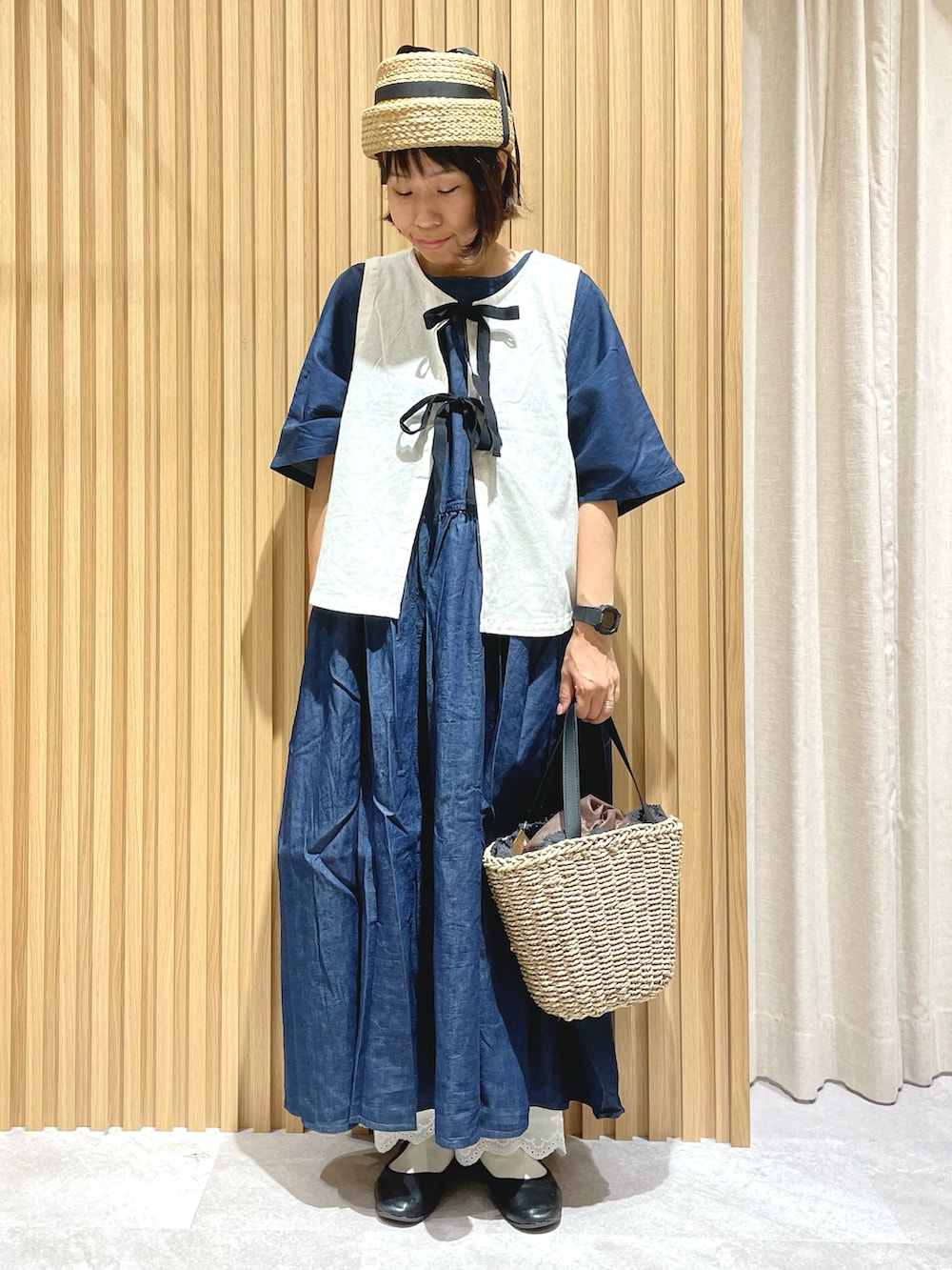 ブラック系のハンドバッグ、ホワイト系のベスト、ブルー系のワンピースを着用したレディースの夏コーディネートの3枚目の写真