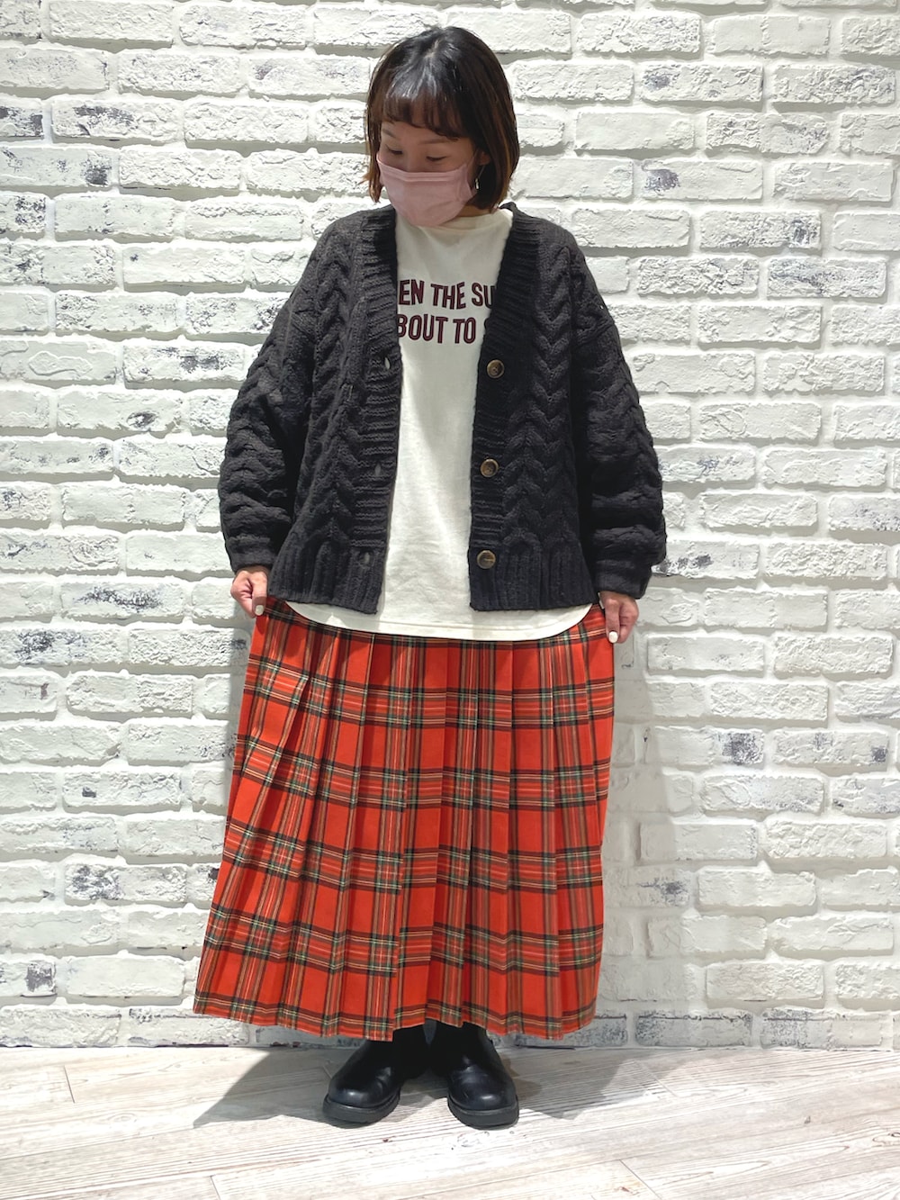 ホワイト系のTシャツ/カットソー、グレー系のカーディガン/ボレロ、ブラック系のブーツを着用したレディースの冬コーディネートの2枚目の写真