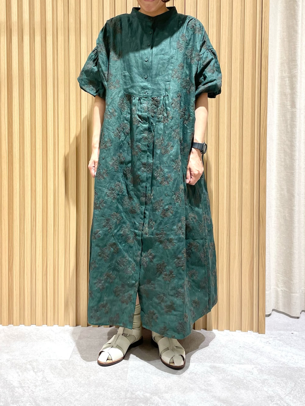 グリーン系のワンピース、ホワイト系のサンダル、ブラック系のハットを着用したレディースの春コーディネートの2枚目の写真