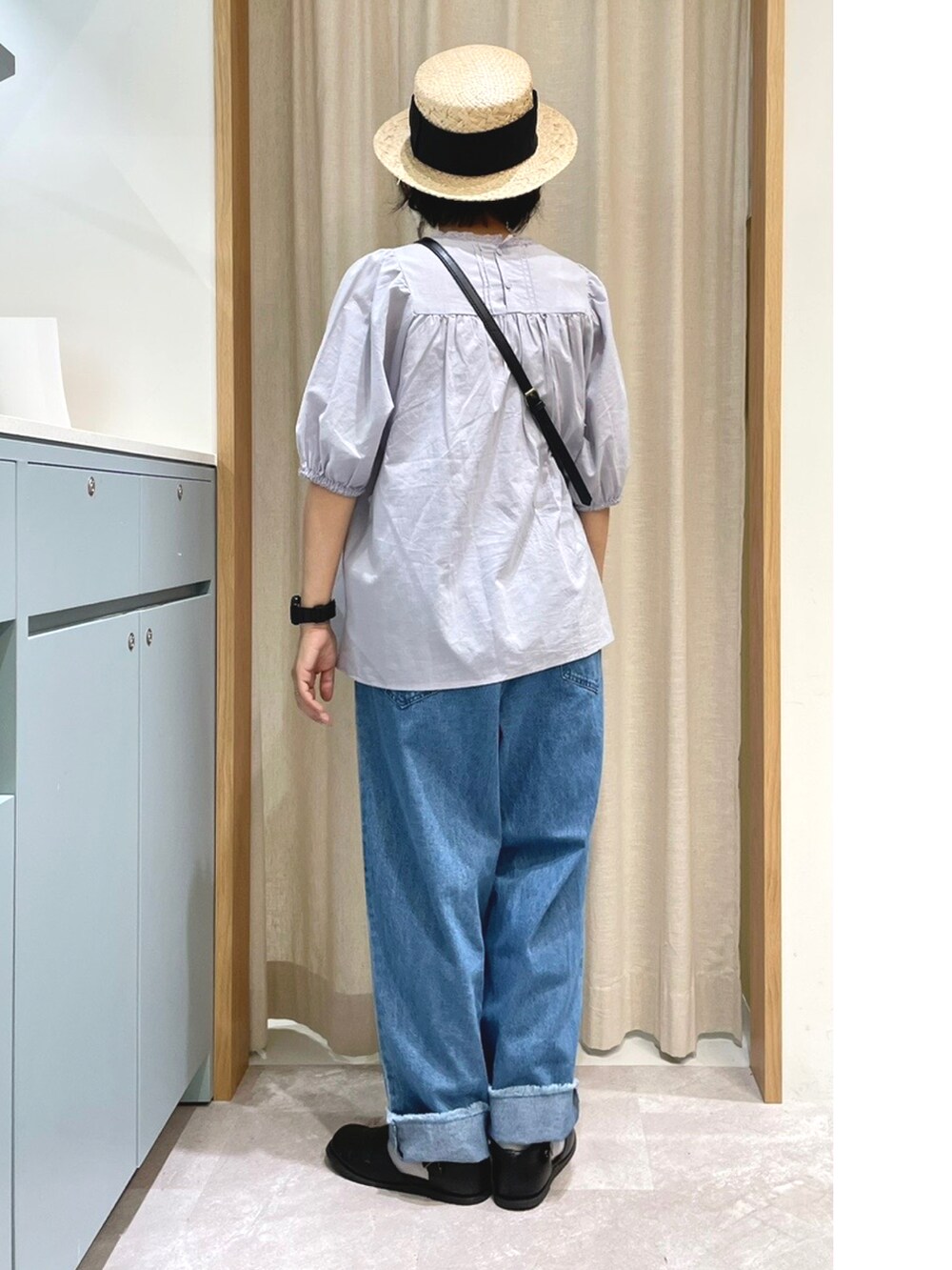 ブルー系のシャツ/ブラウス、ブラック系のハンドバッグ、ブルー系のデニムパンツを着用したレディースの夏コーディネートの2枚目の写真