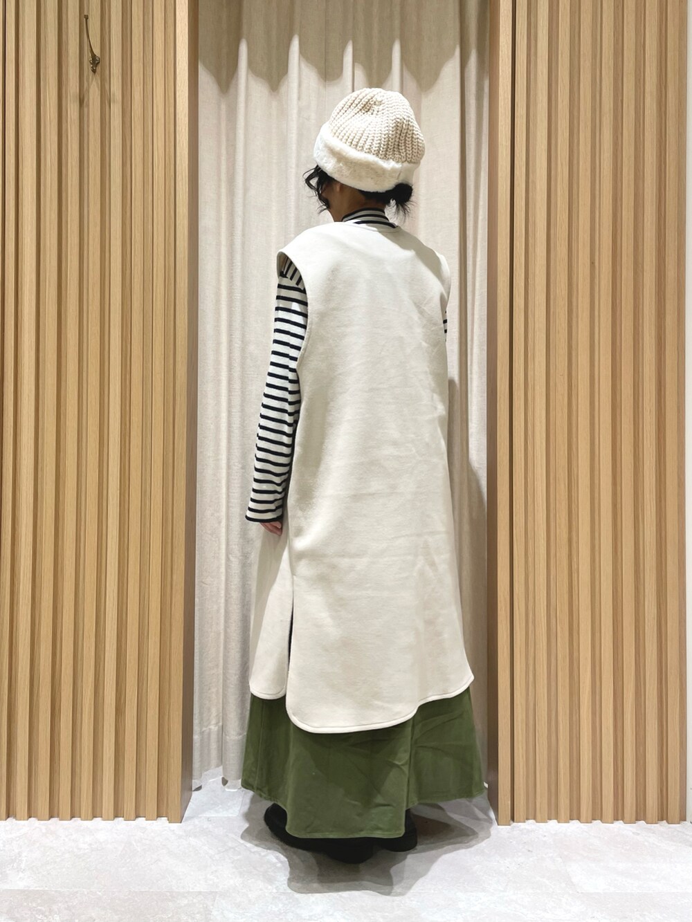 ブルー系のニット/セーター、グリーン系のワンピース、ホワイト系のベストを着用したレディースの冬コーディネートの4枚目の写真