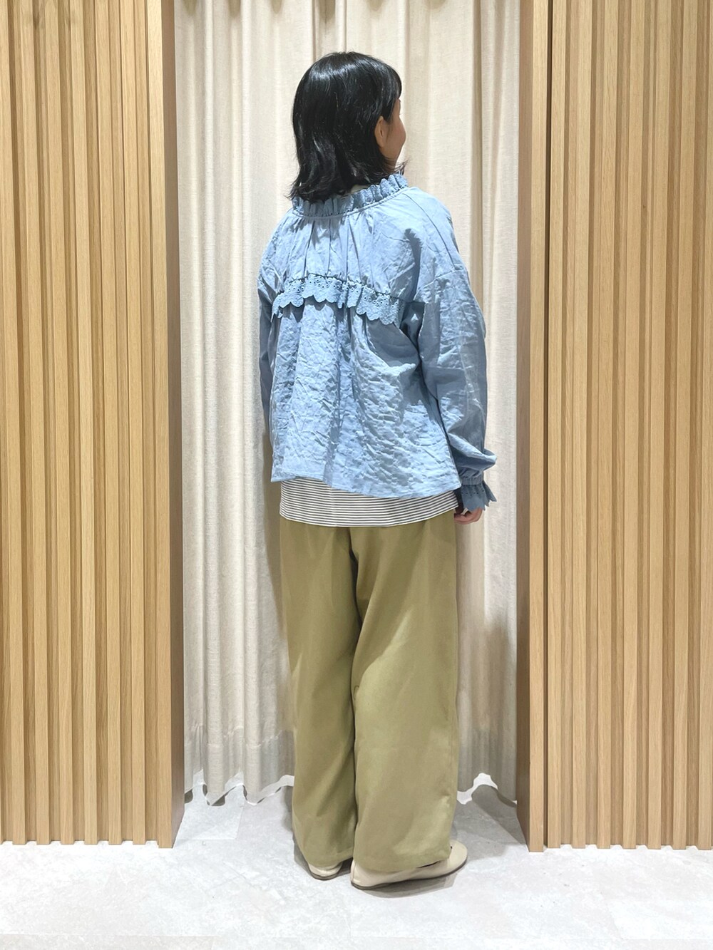 ブルー系のTシャツ/カットソー、ブルー系のシャツ/ブラウス、ベージュ系のスラックスを着用したレディースの冬コーディネートの3枚目の写真