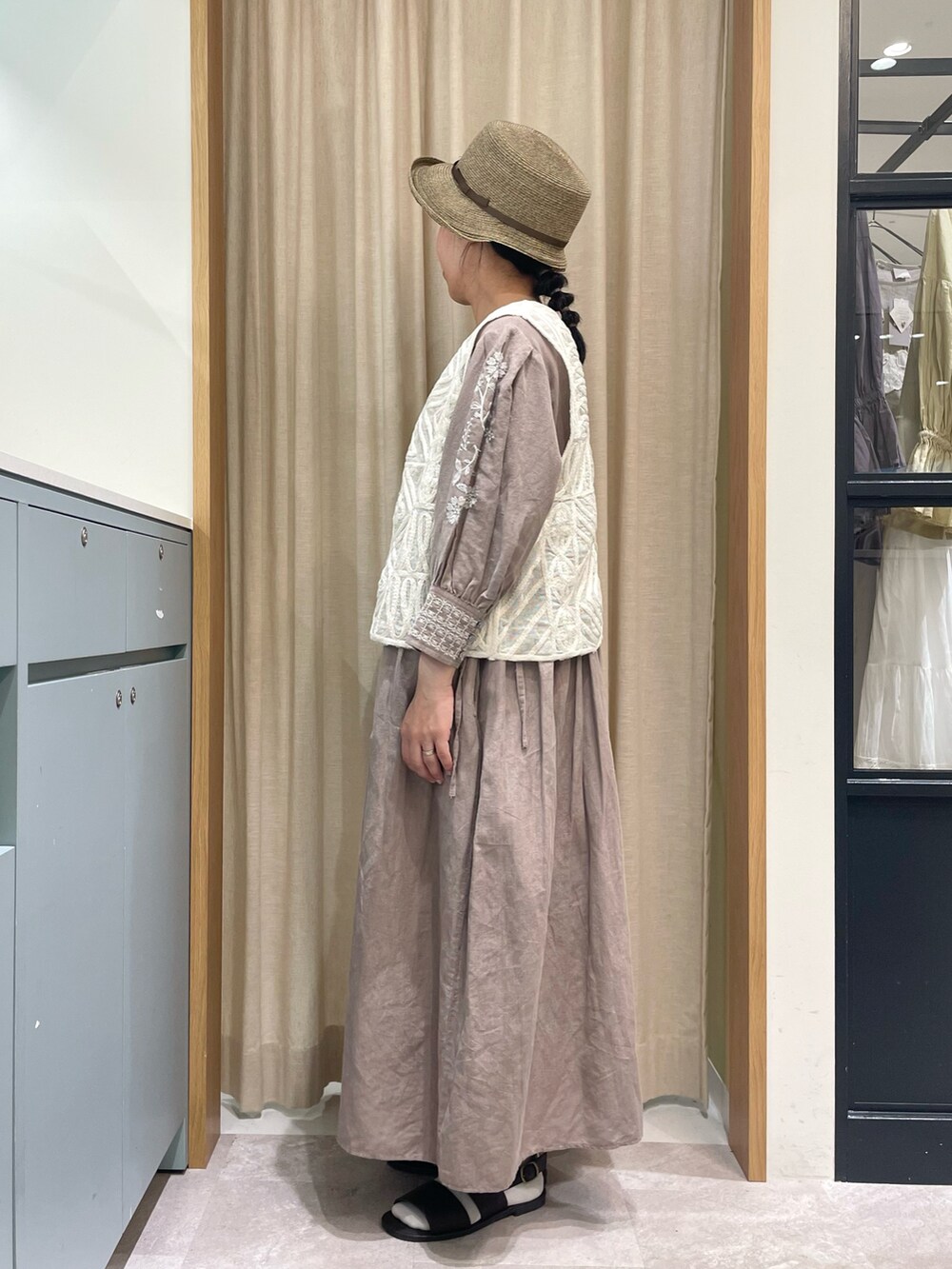 ブラウン系のワンピース、ホワイト系のベスト、ブラウン系のサンダルを着用したレディースの夏コーディネートの3枚目の写真