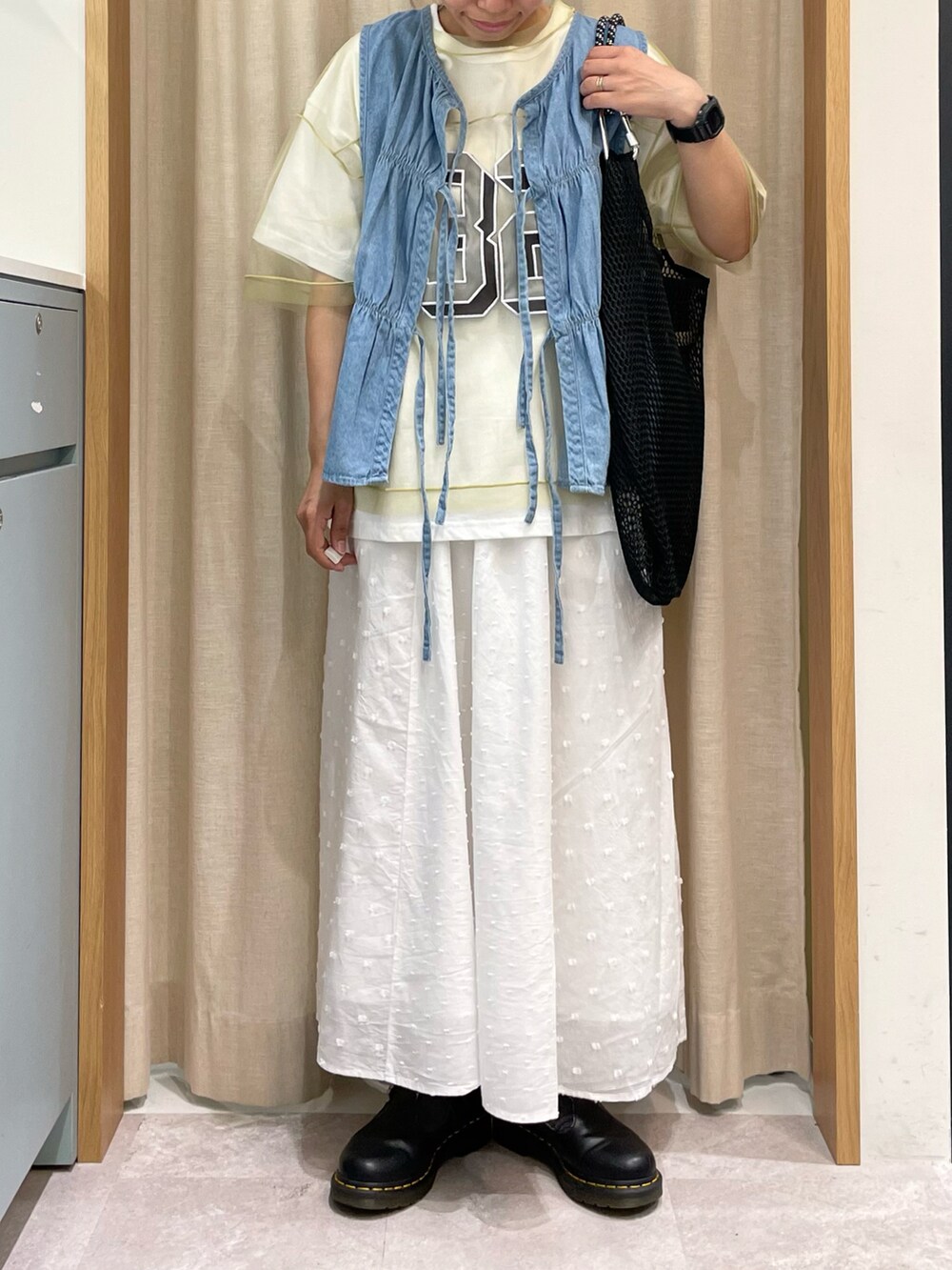 グリーン系のTシャツ/カットソー、ブルー系のベスト、ブラック系のハンドバッグを着用したレディースの春コーディネートの2枚目の写真